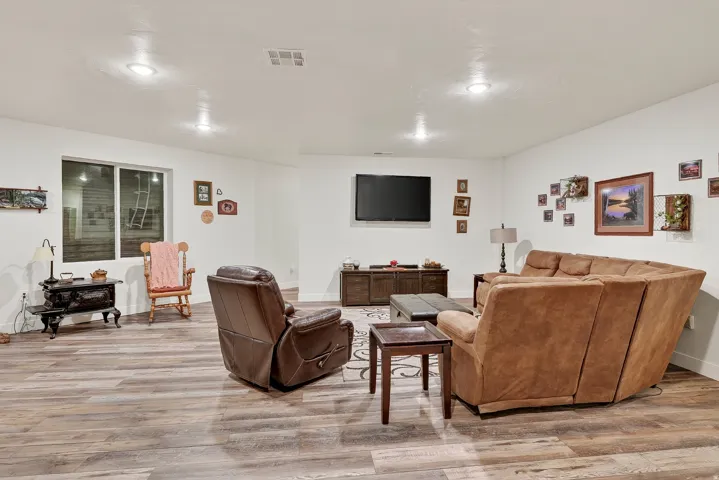 Spacious entertainment area featuring wood-finish flooring, recessed lighting, and a window