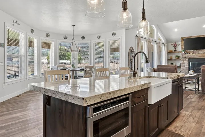 Kitchen island featuring a farmhouse sink, granite countertops, and built-in microwave drawer