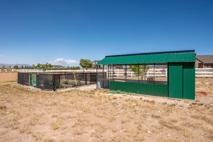 Utility structure featuring a green metal roof and green paneling, with an attached screened enclosure