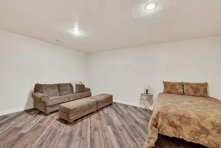Spacious room featuring wood-finish flooring, white walls, and recessed lighting