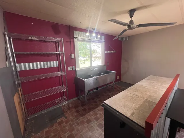 Dual-basin utility sink, tiled countertop, and overhead ceiling fan