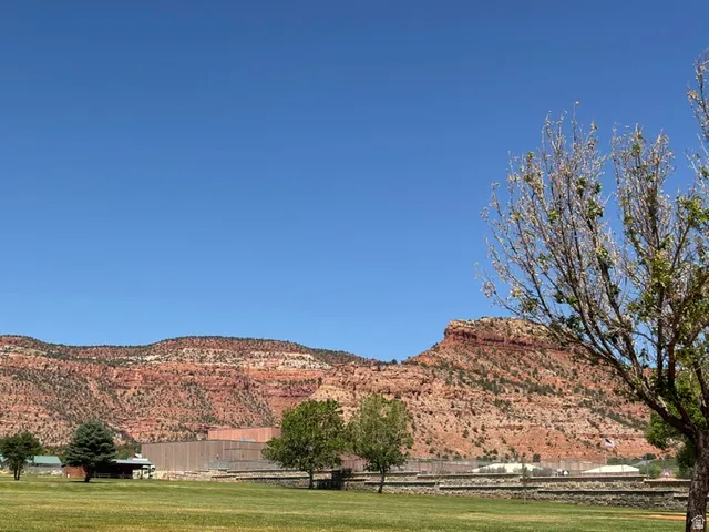 Expansive green lawn with mature trees and a distant mountainous backdrop