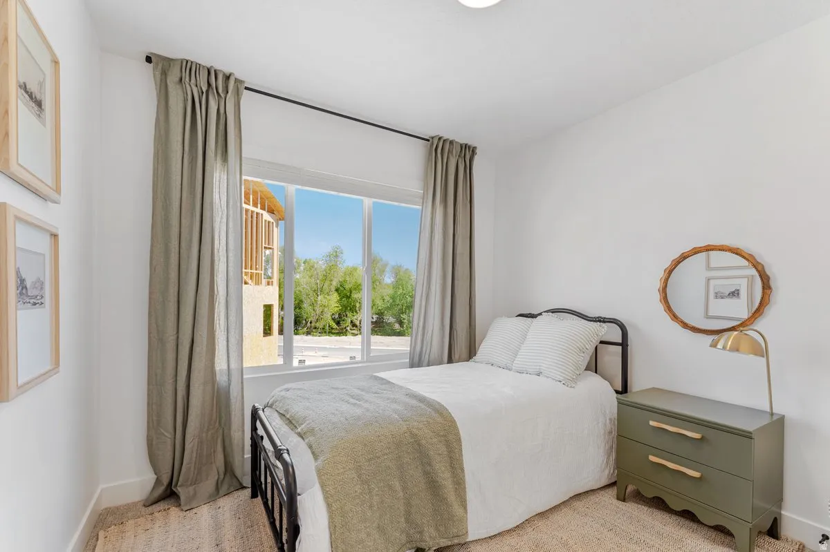 Bright bedroom featuring a large window with ample natural light, neutral wall colors, recessed lighting, and light-toned carpet flooring