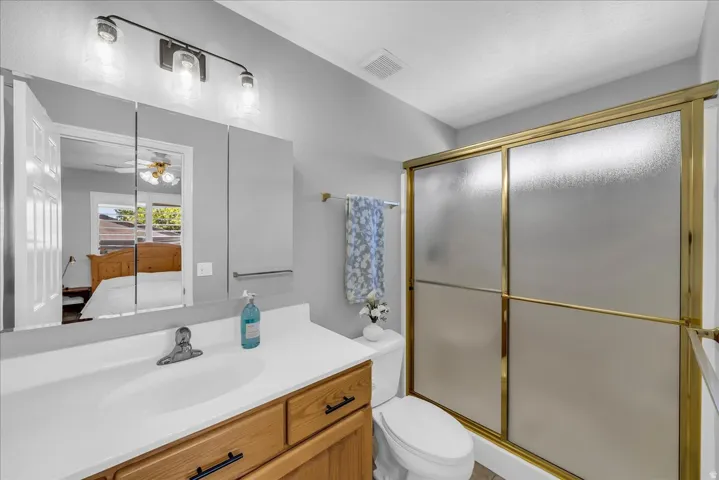 Bathroom featuring a single vanity with a white countertop, wood-finish cabinetry, and a mirrored medicine cabinet