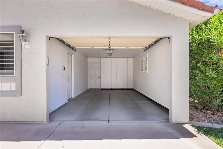 Two-car garage with concrete flooring, interior access door, accordion-style storage doors, and a window with horizontal blinds