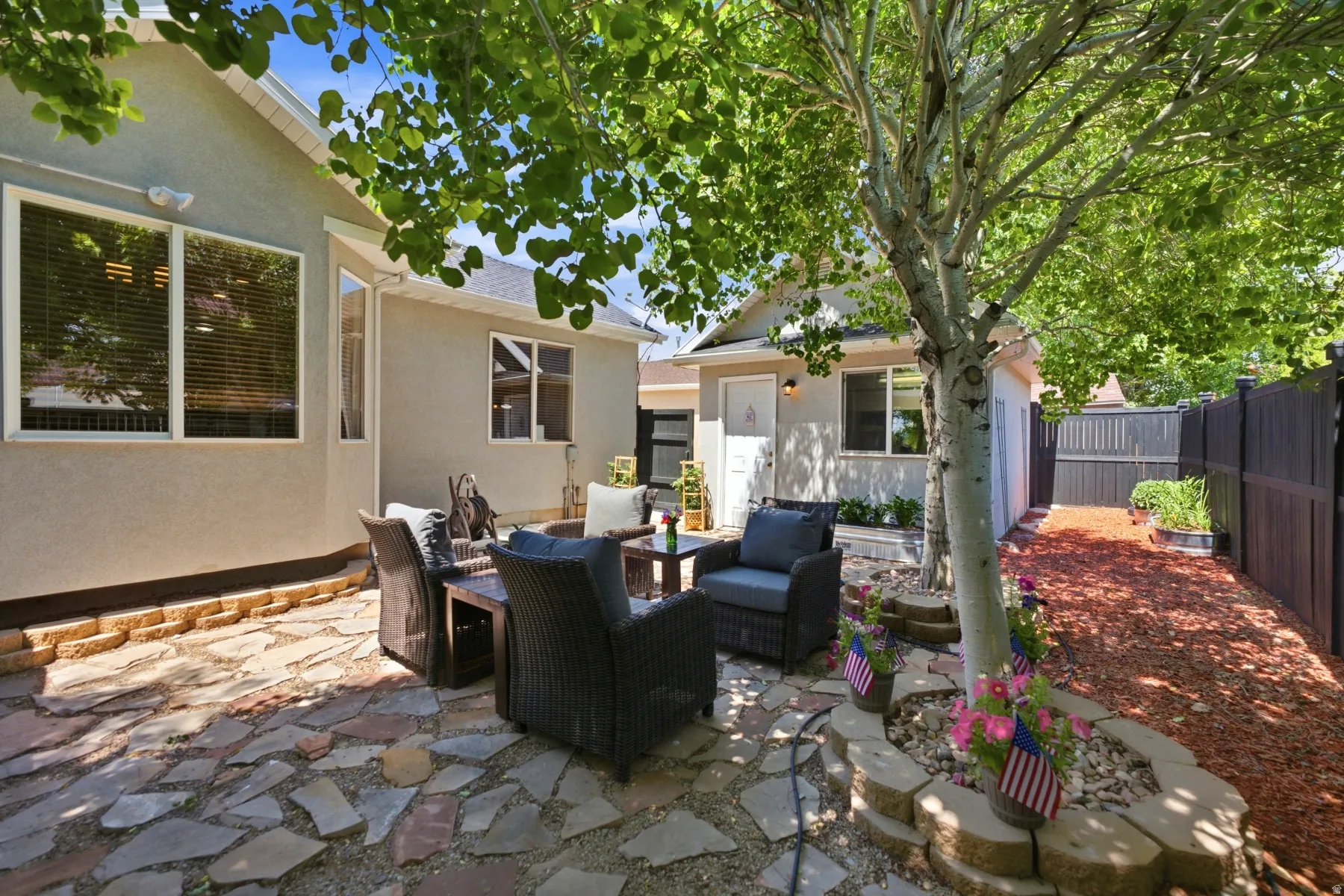 Patio space with flagstone pavers, surrounded by stucco exterior and a dark privacy fence