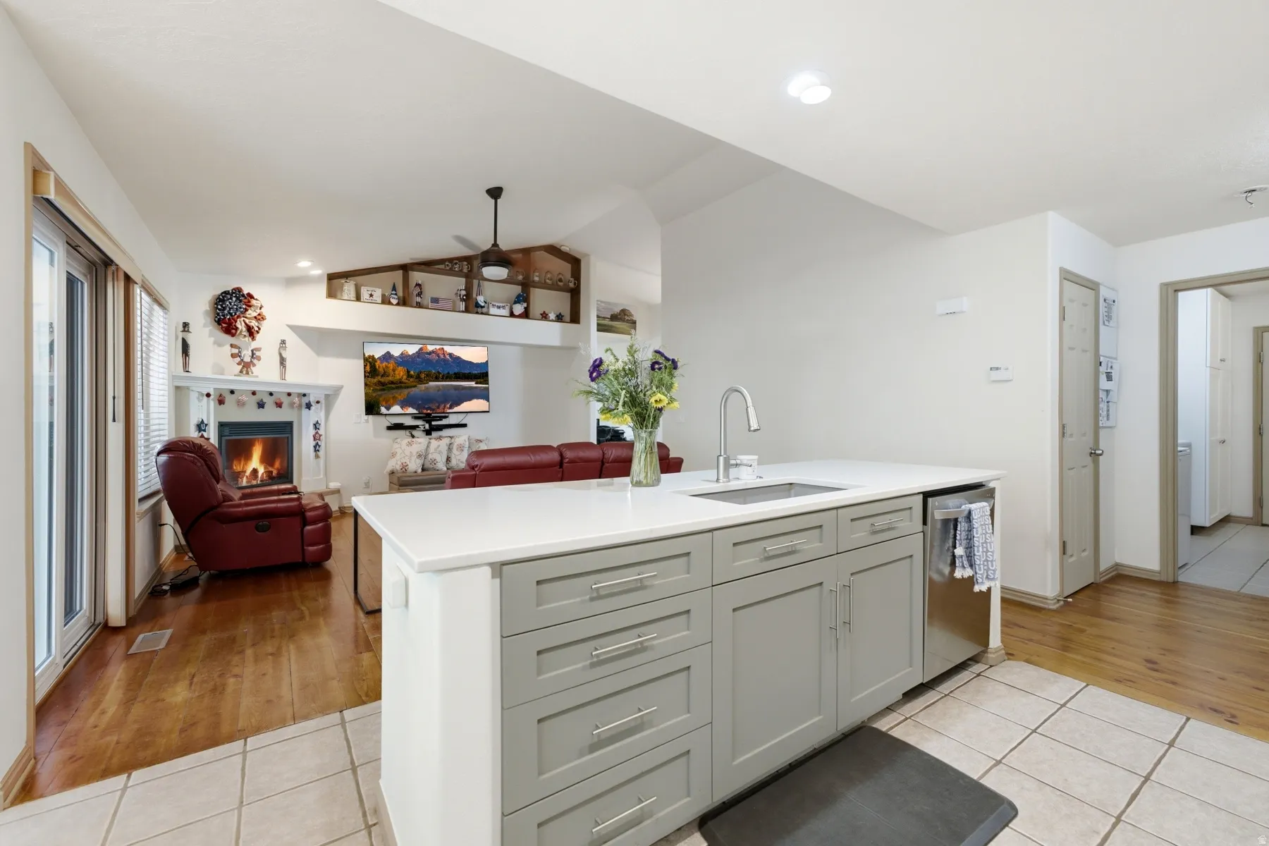 Kitchen island featuring a single-basin sink with a gooseneck faucet, light gray cabinetry, and a white countertop