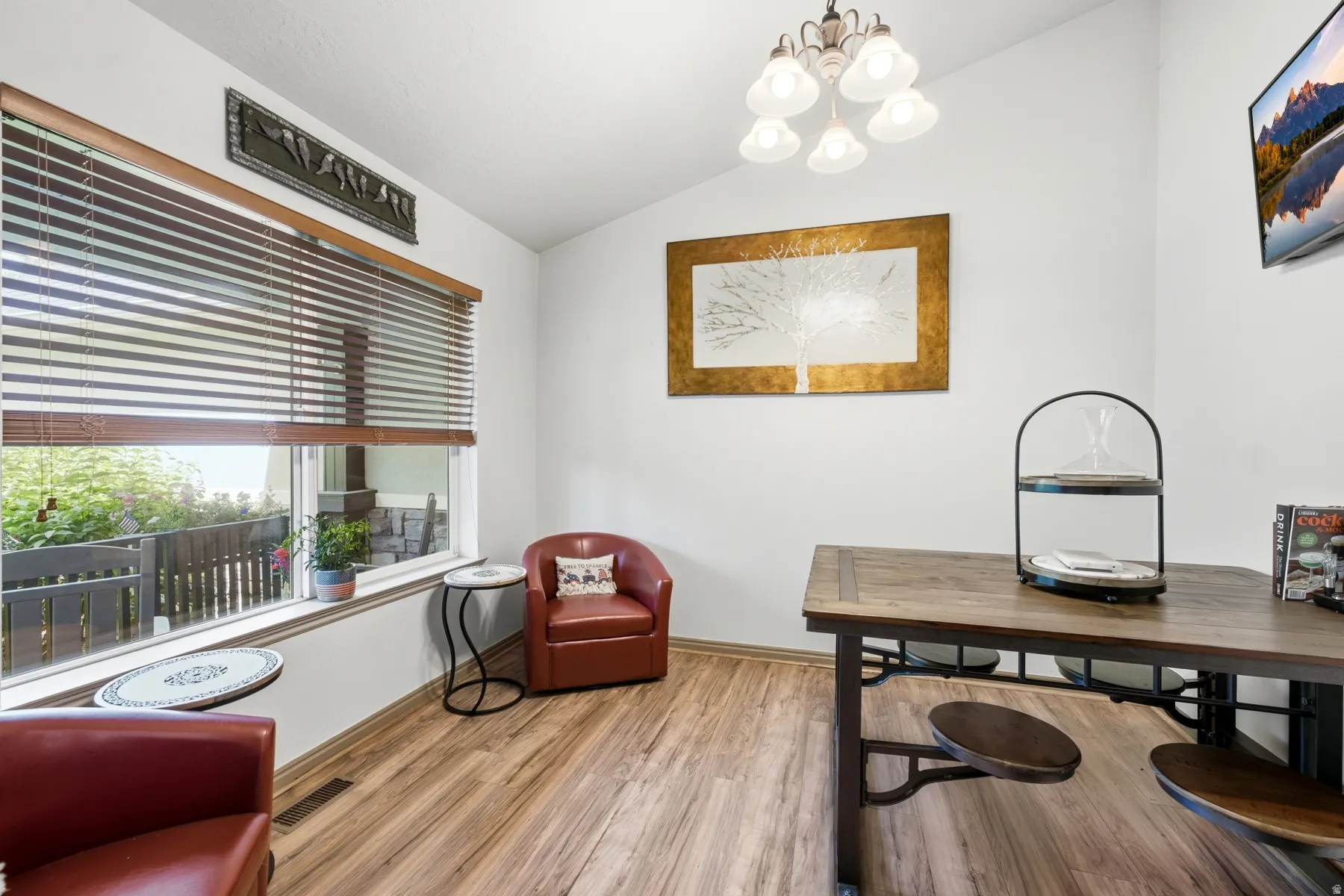 Bright interior space featuring wood-finish flooring and a large window with horizontal blinds