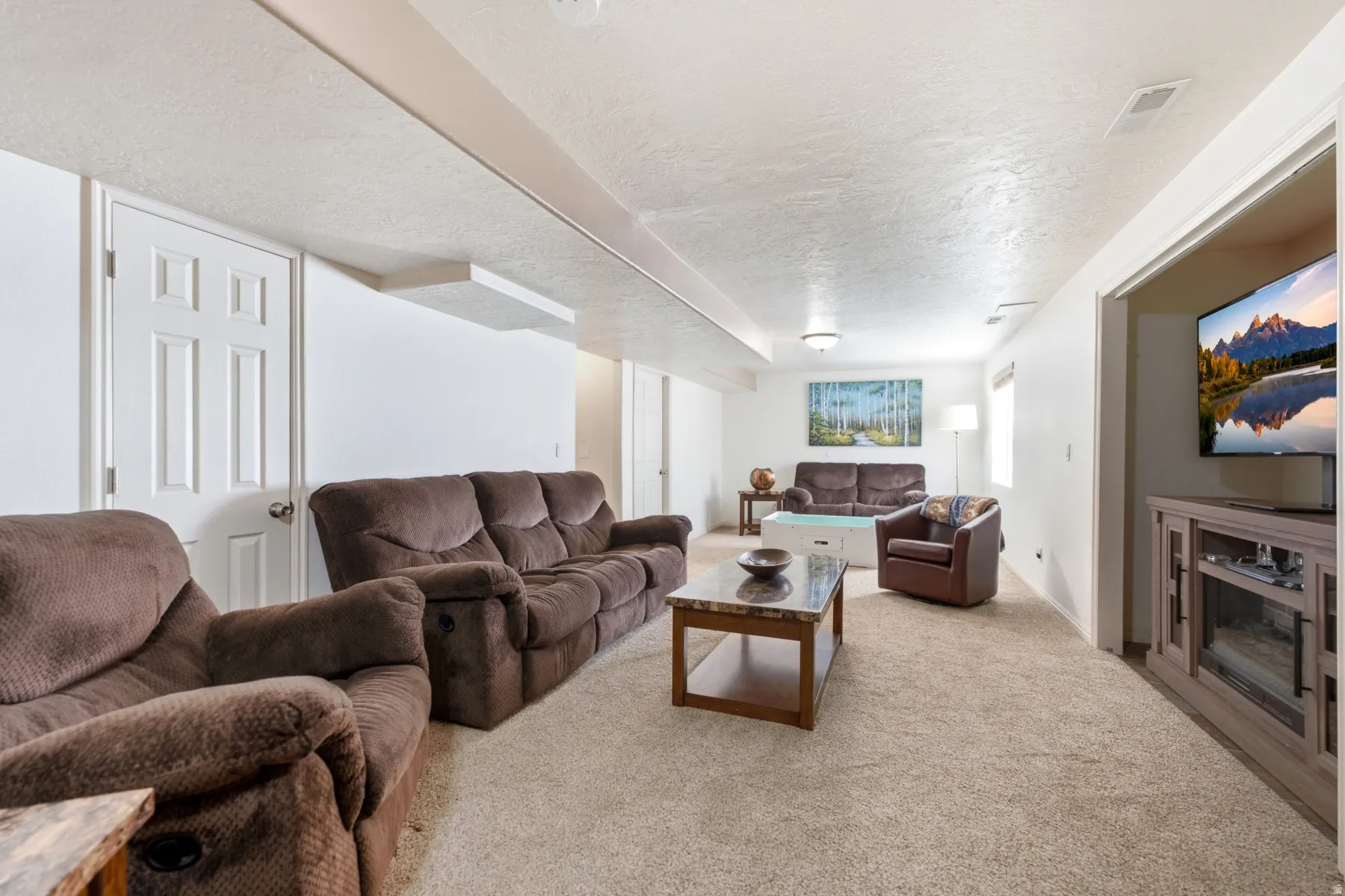 Spacious lower-level area with neutral carpeting, white walls, and recessed lighting