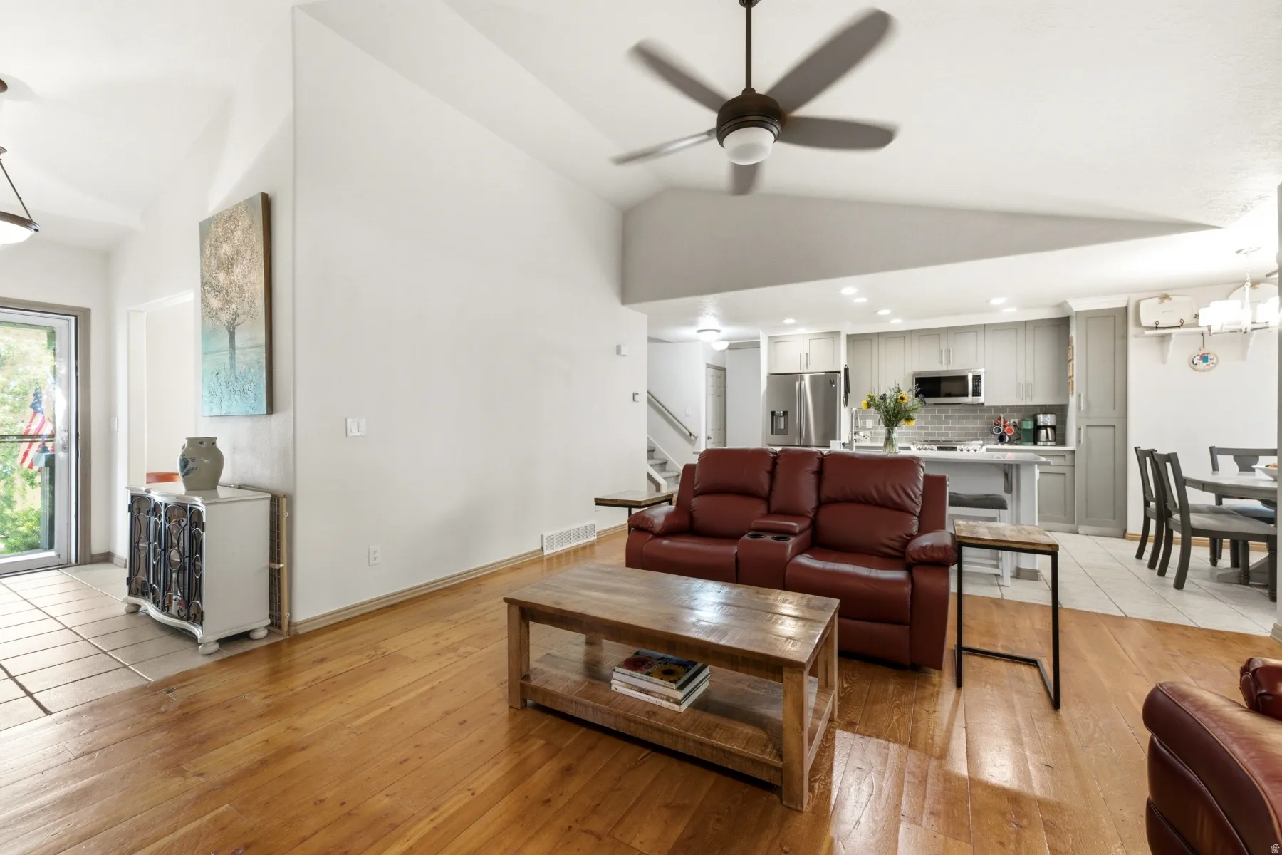 Expansive living area featuring vaulted ceilings, wood-finish flooring, and a ceiling fan
