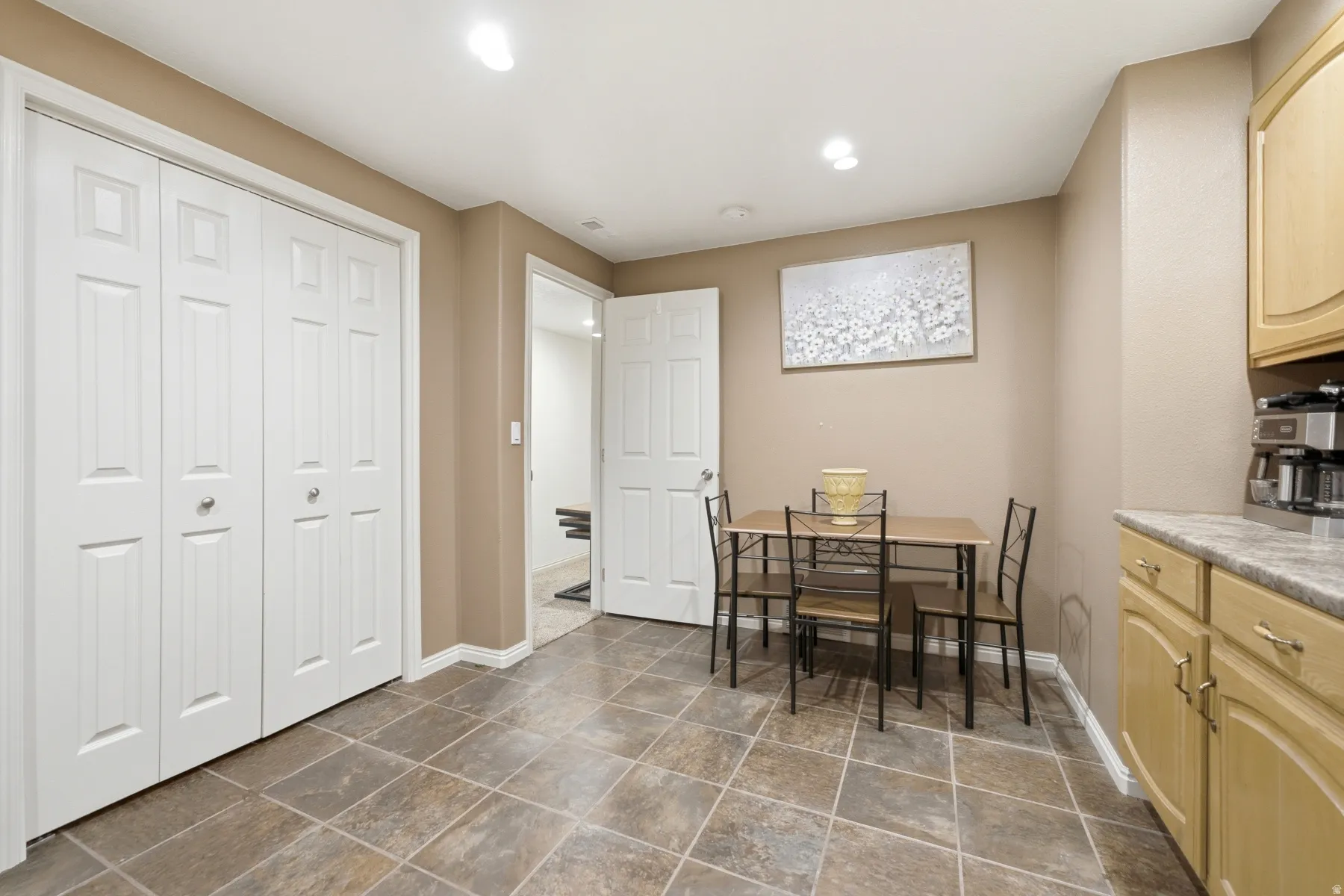 Spacious room featuring neutral wall tones, square tile flooring, white bi-fold closet doors, and recessed lighting