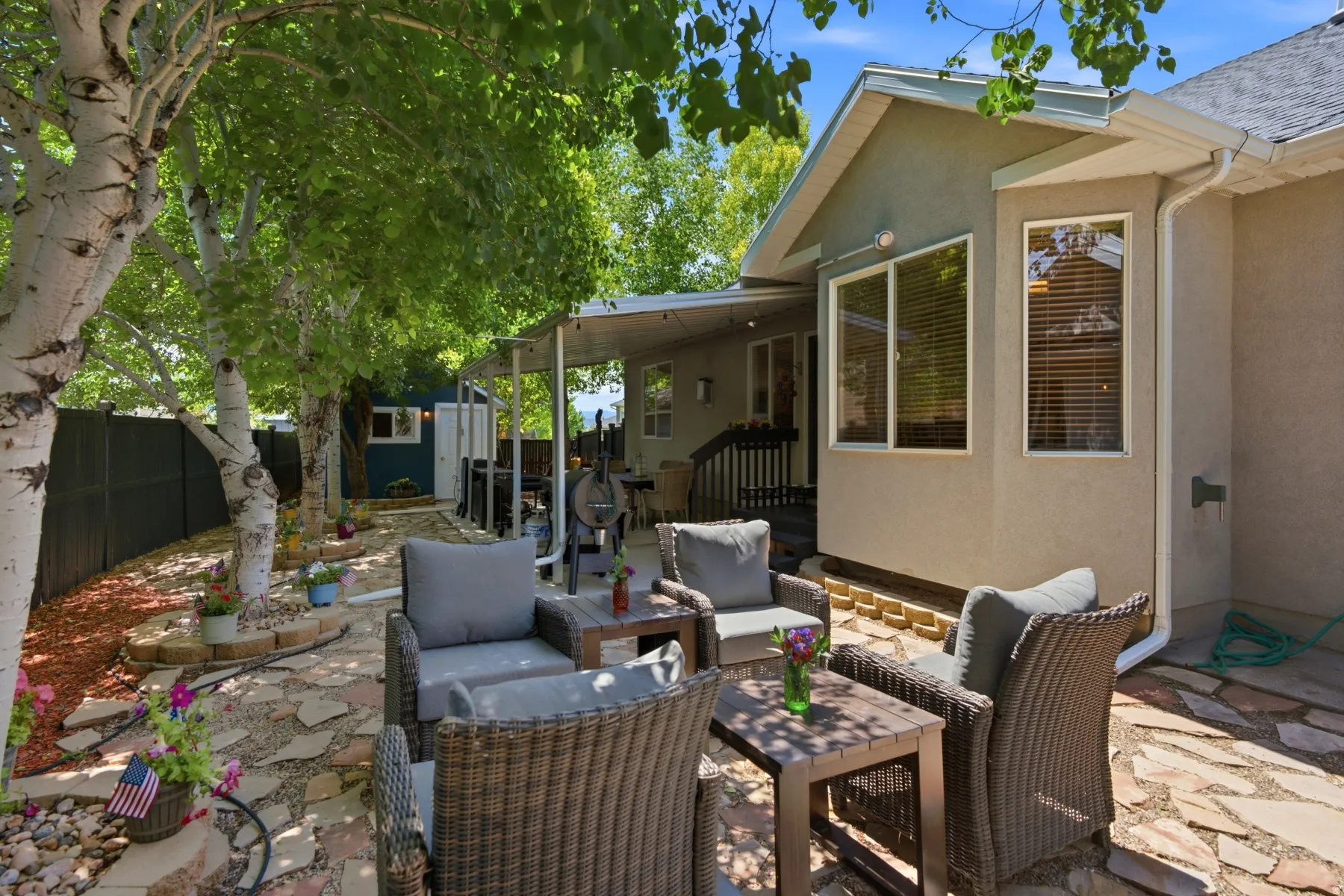 Expansive flagstone patio area with a covered outdoor space and mature trees