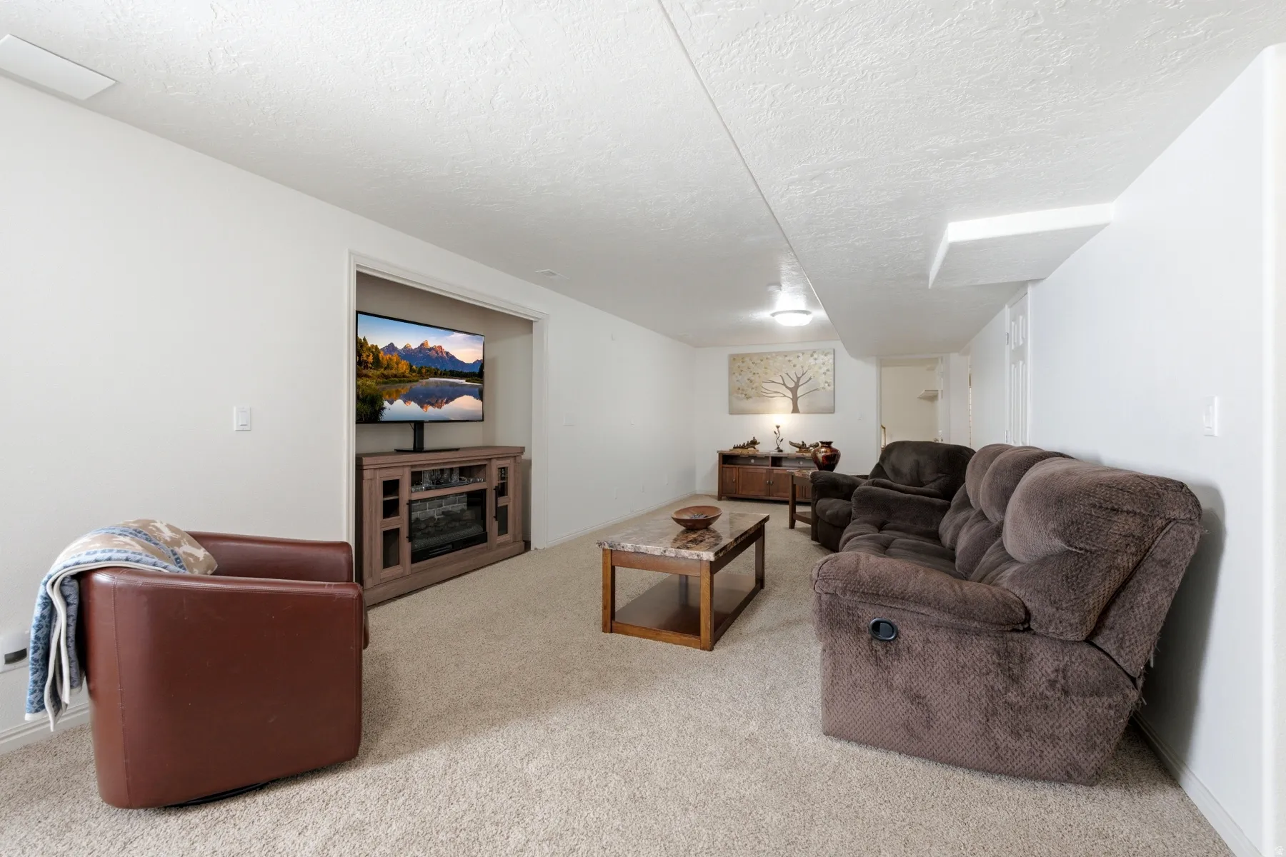 Carpeted living area featuring white walls and a textured ceiling