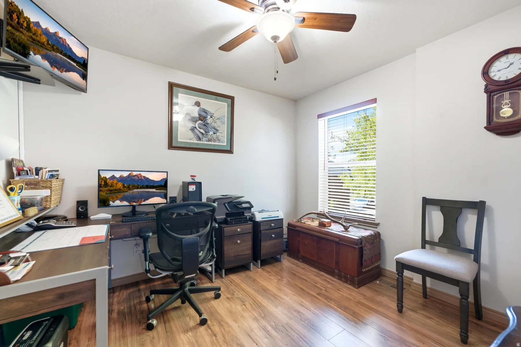 Bedroom currently used as an office . Interior room with wood-finish flooring and a ceiling fan