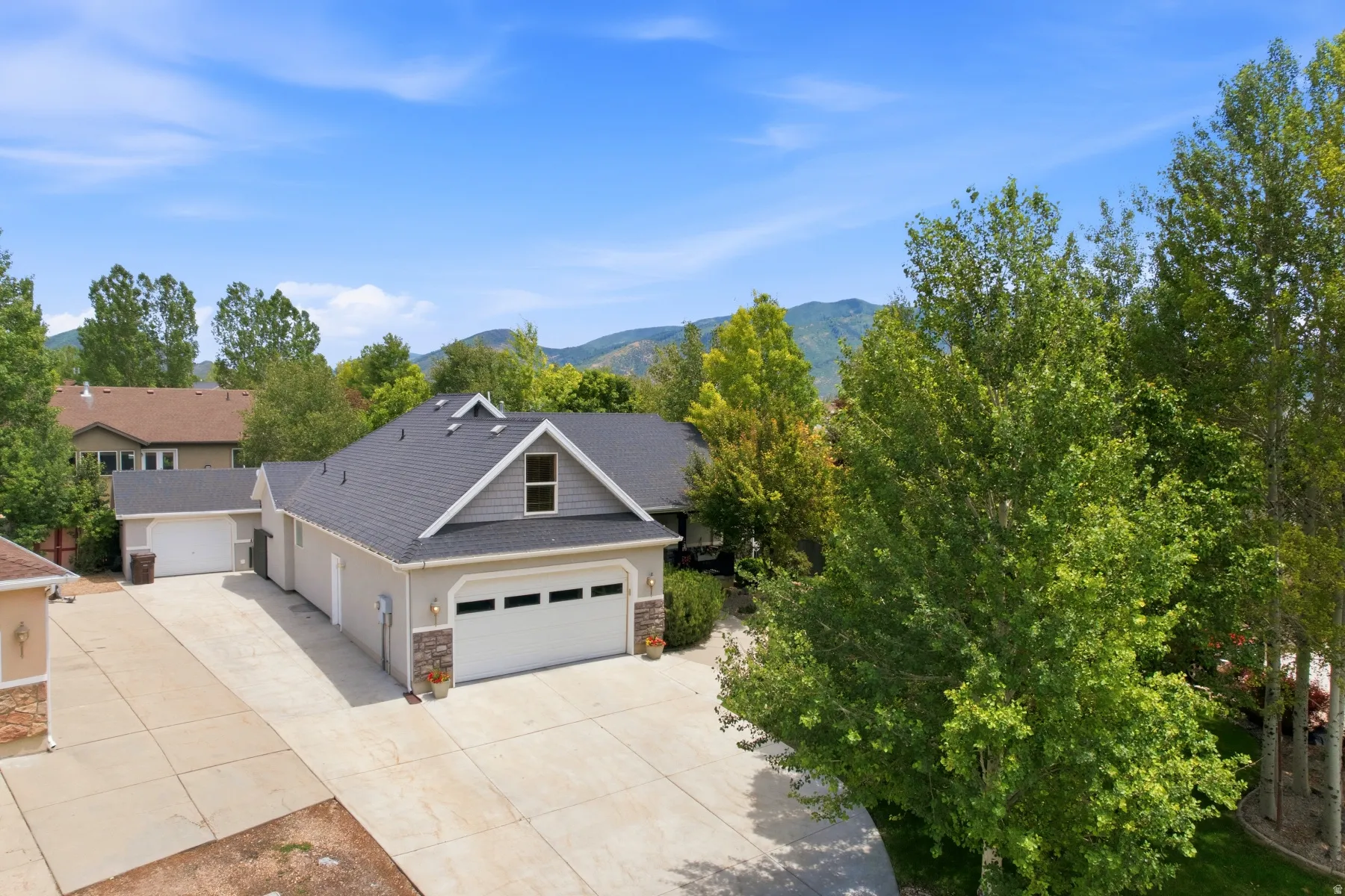 Contemporary-style residence featuring a dark shingled roof, light stucco siding, and stone accents