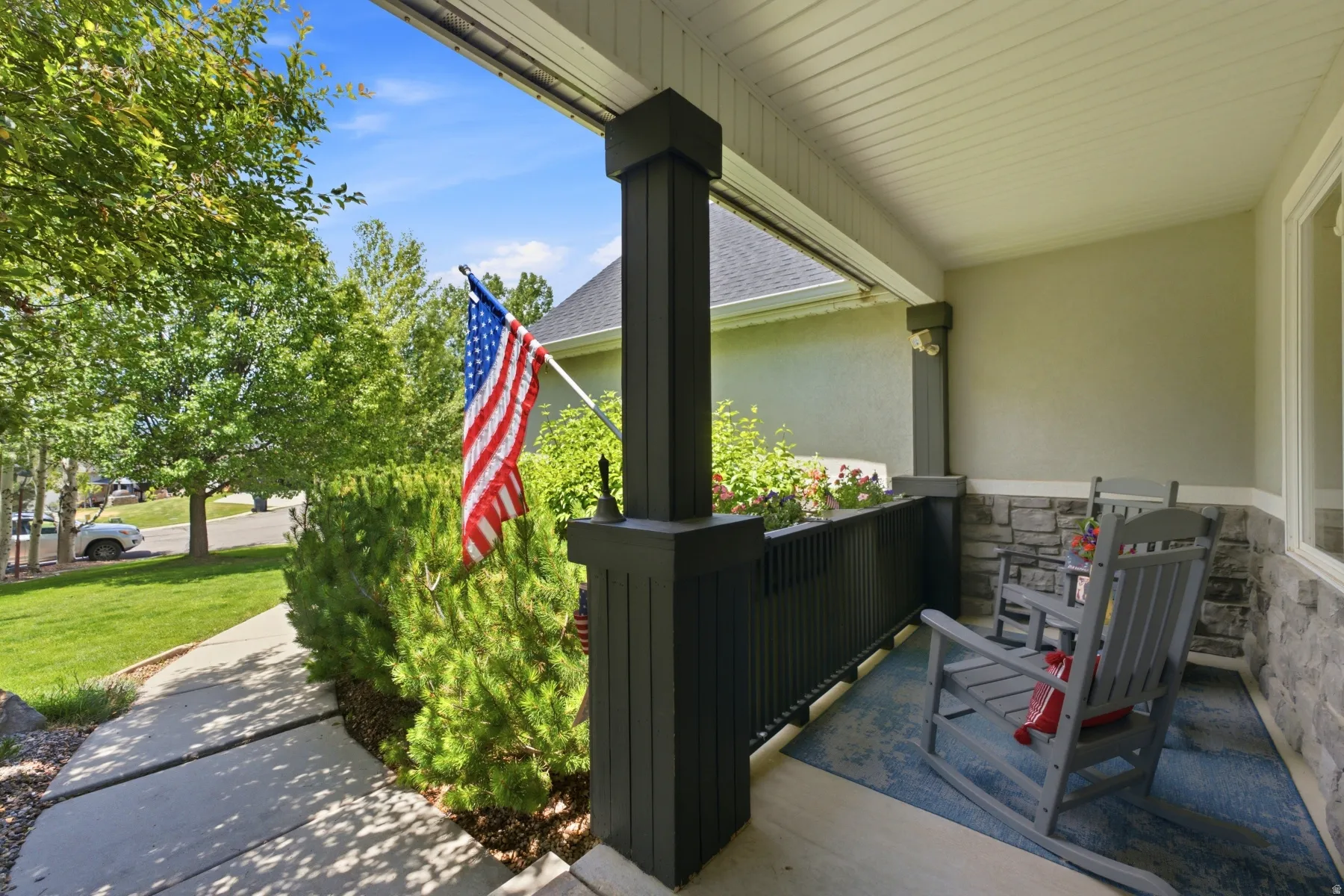 Covered front porch featuring stone veneer accents and a painted concrete floor