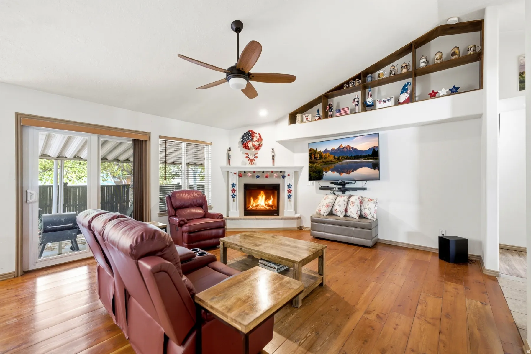 Spacious living area featuring a fireplace with a decorative mantel, vaulted ceilings, and built-in display shelving