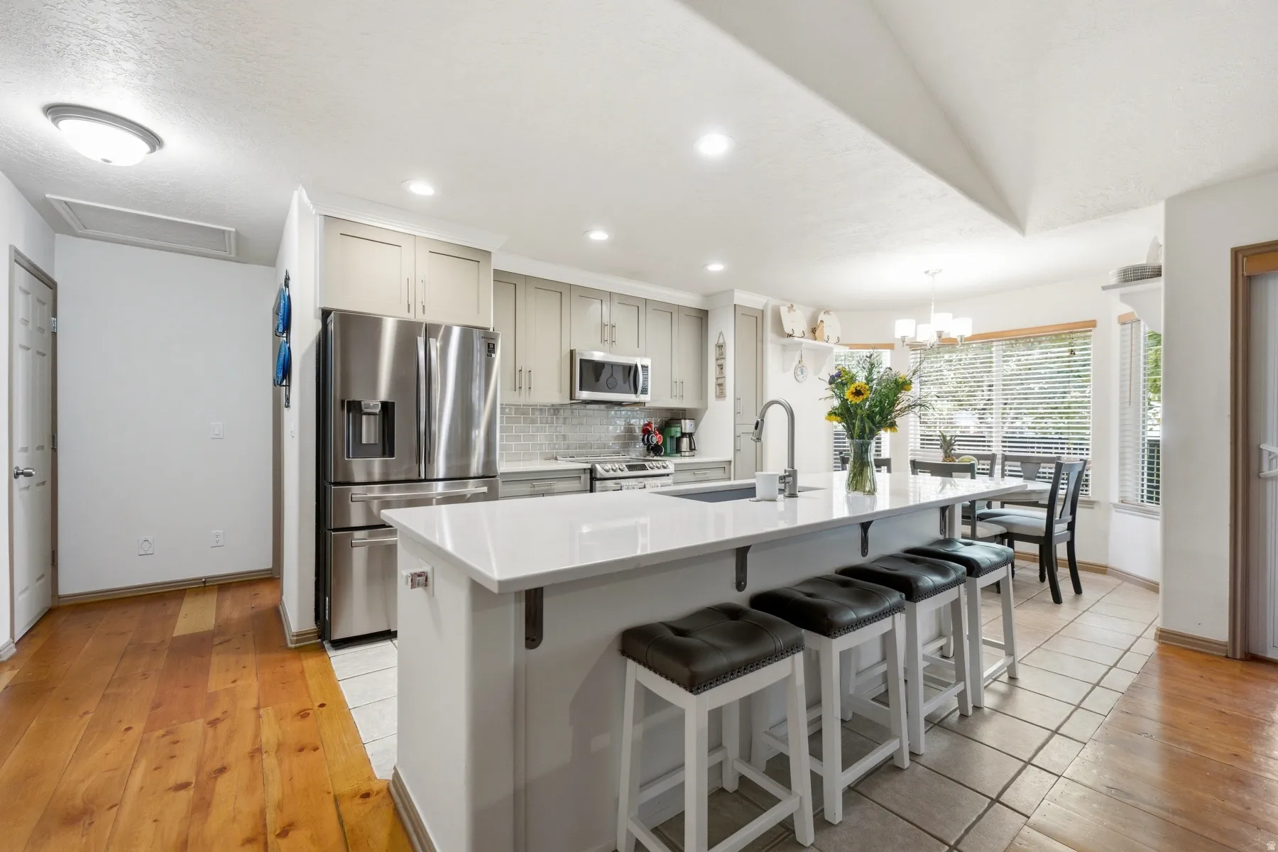 Kitchen featuring a central island with countertop seating, stainless steel appliances, light-toned cabinetry, a subway tile backsplash, and recessed lighting