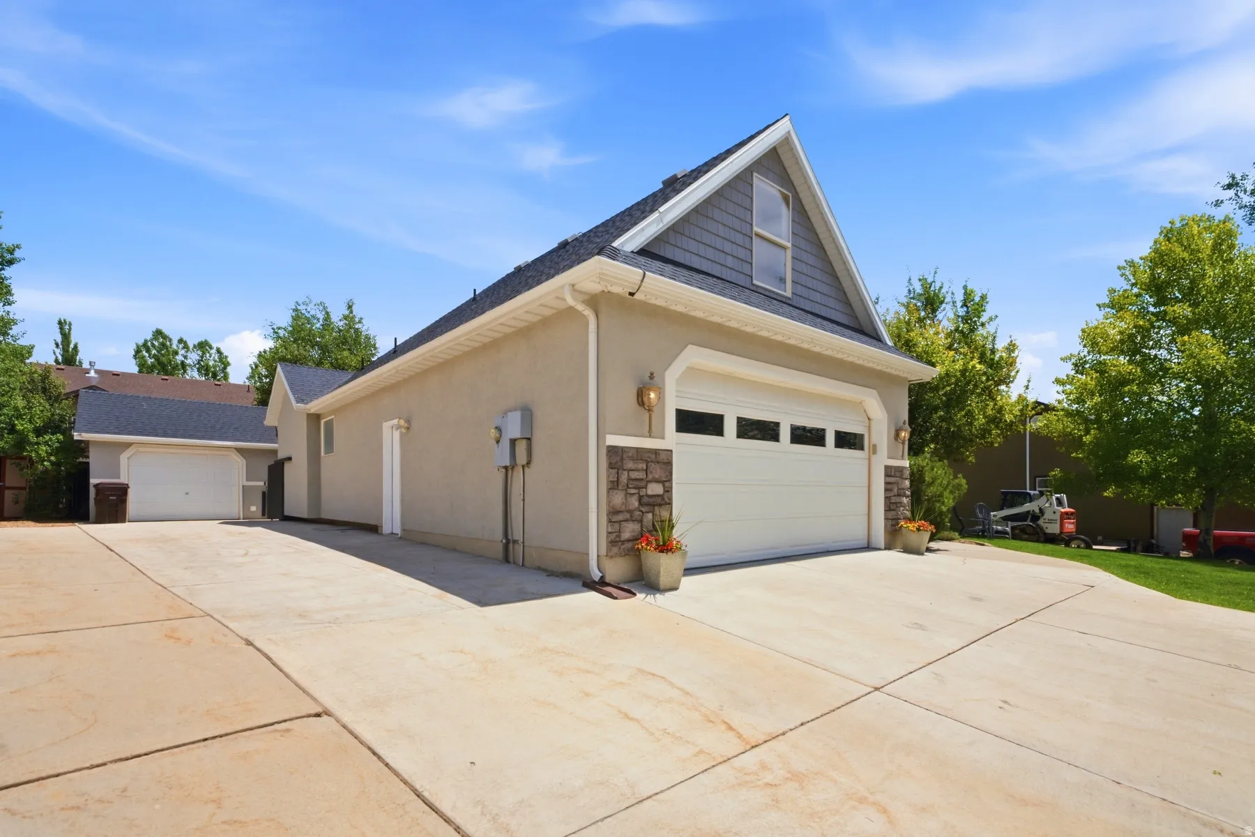 Two-car garage with stone accents and an additional detached garage structure