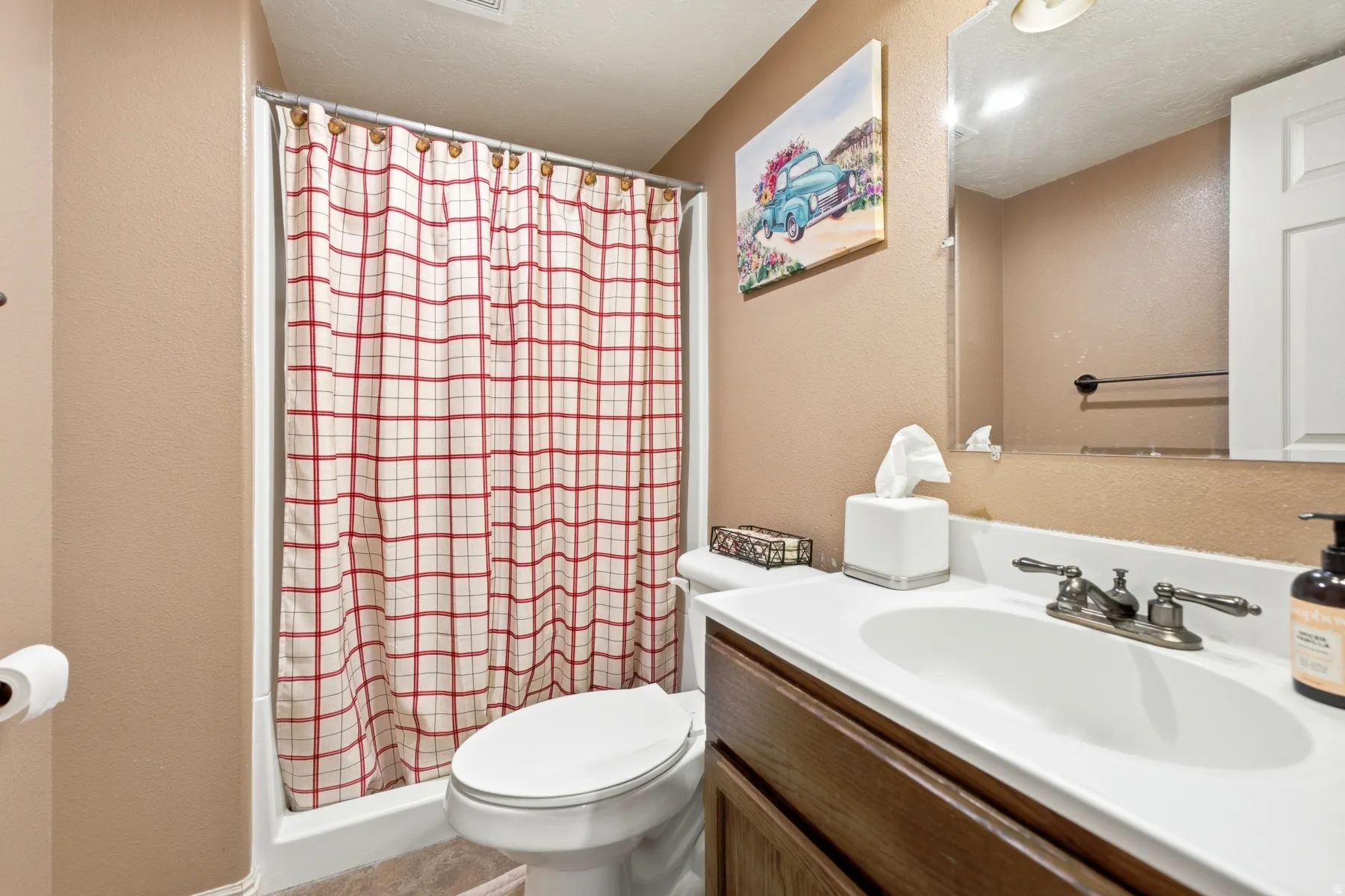 Full bathroom featuring a shower/tub combination with a white surround, a toilet, and a vanity with a white countertop and integrated sink