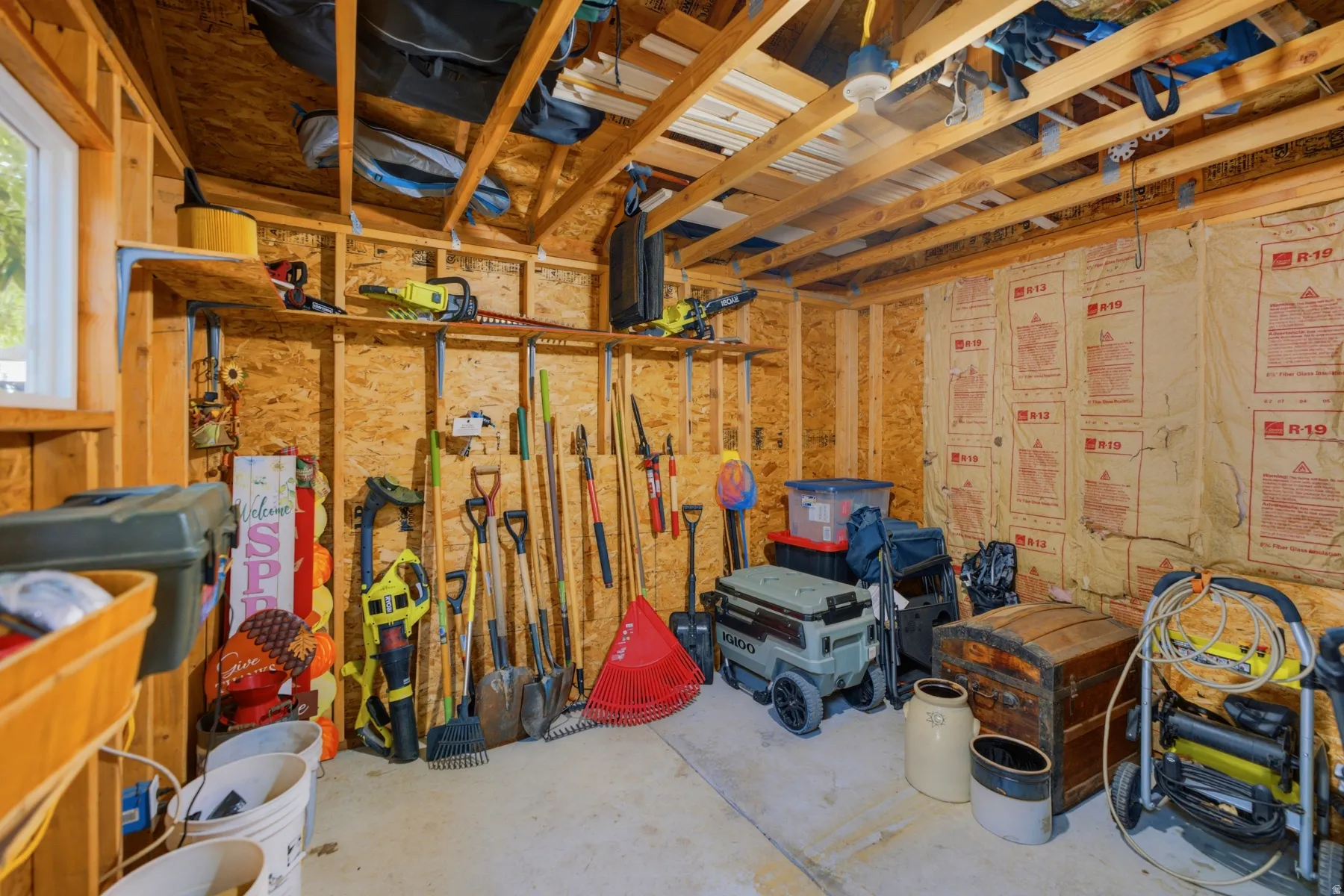 Utility building interior with exposed wood framing, oriented strand board walls, and concrete flooring