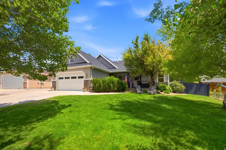 Two-story residence featuring a gray exterior with stone accents, a dark shingle roof, and a prominent attached two-car garage