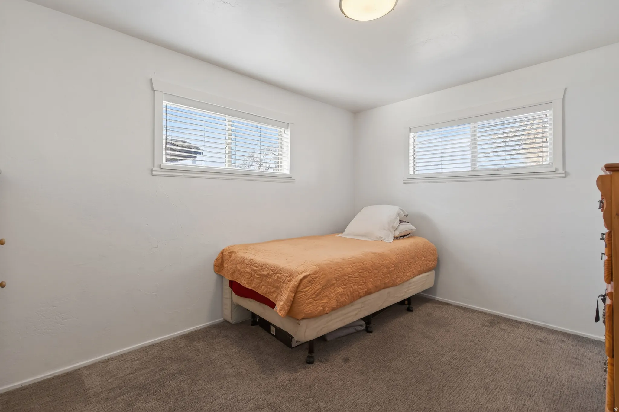 Bright room with two horizontal windows, each featuring white blinds