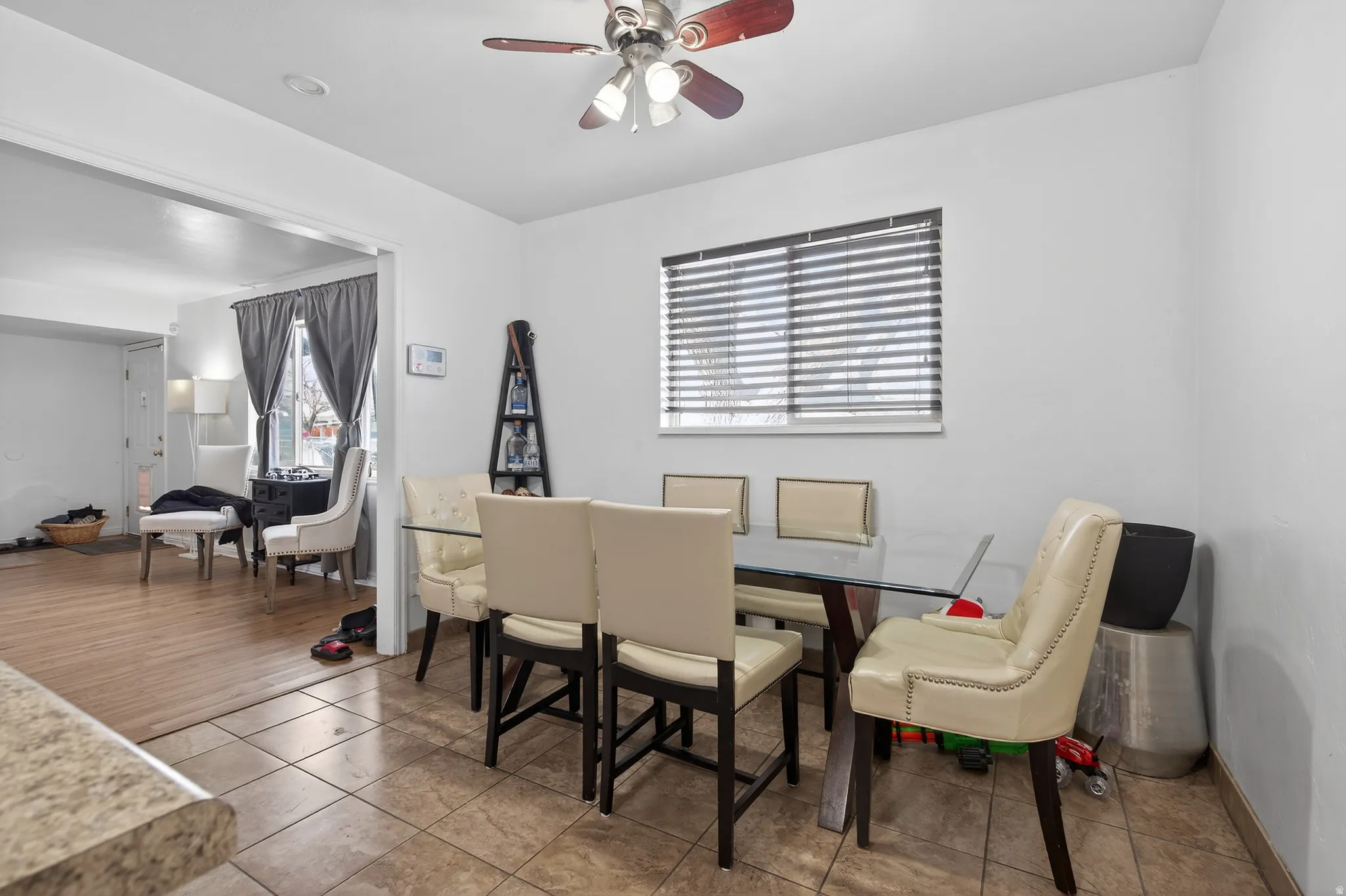 Dining area featuring ceramic tile flooring, a window with horizontal blinds, and a ceiling fan with integrated lighting