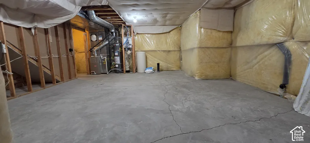 Unfinished basement space featuring a concrete floor, exposed wood framing, and insulated walls