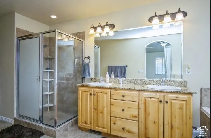 Dual vanity with a stone-finish countertop, wood-finish cabinetry, and framed mirror