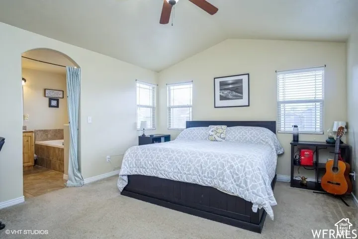 Vaulted ceiling with a ceiling fan, carpeted flooring, and multiple windows with blinds