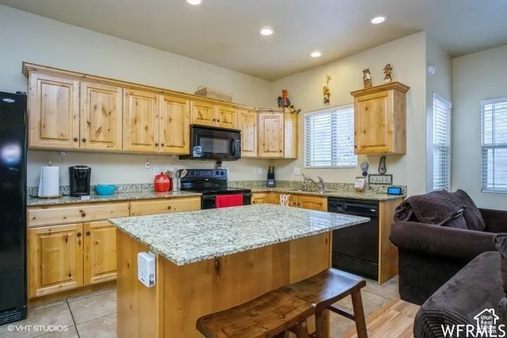 Kitchen featuring wood cabinetry, granite countertops, a central island with countertop seating, and recessed lighting