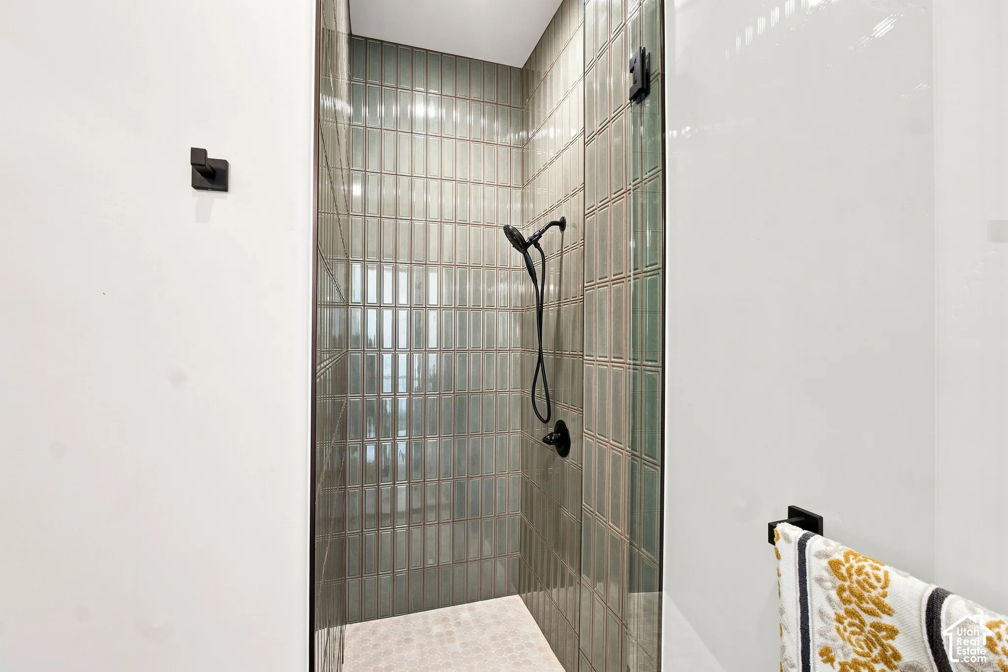 Enclosed shower with full-height tile surround, matte black shower fixtures, and a glass enclosure