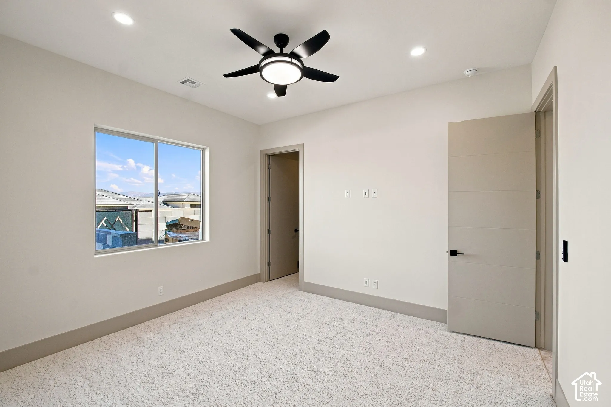 Recessed lighting, ceiling fan, expansive window, neutral wall paint, and textured carpeting