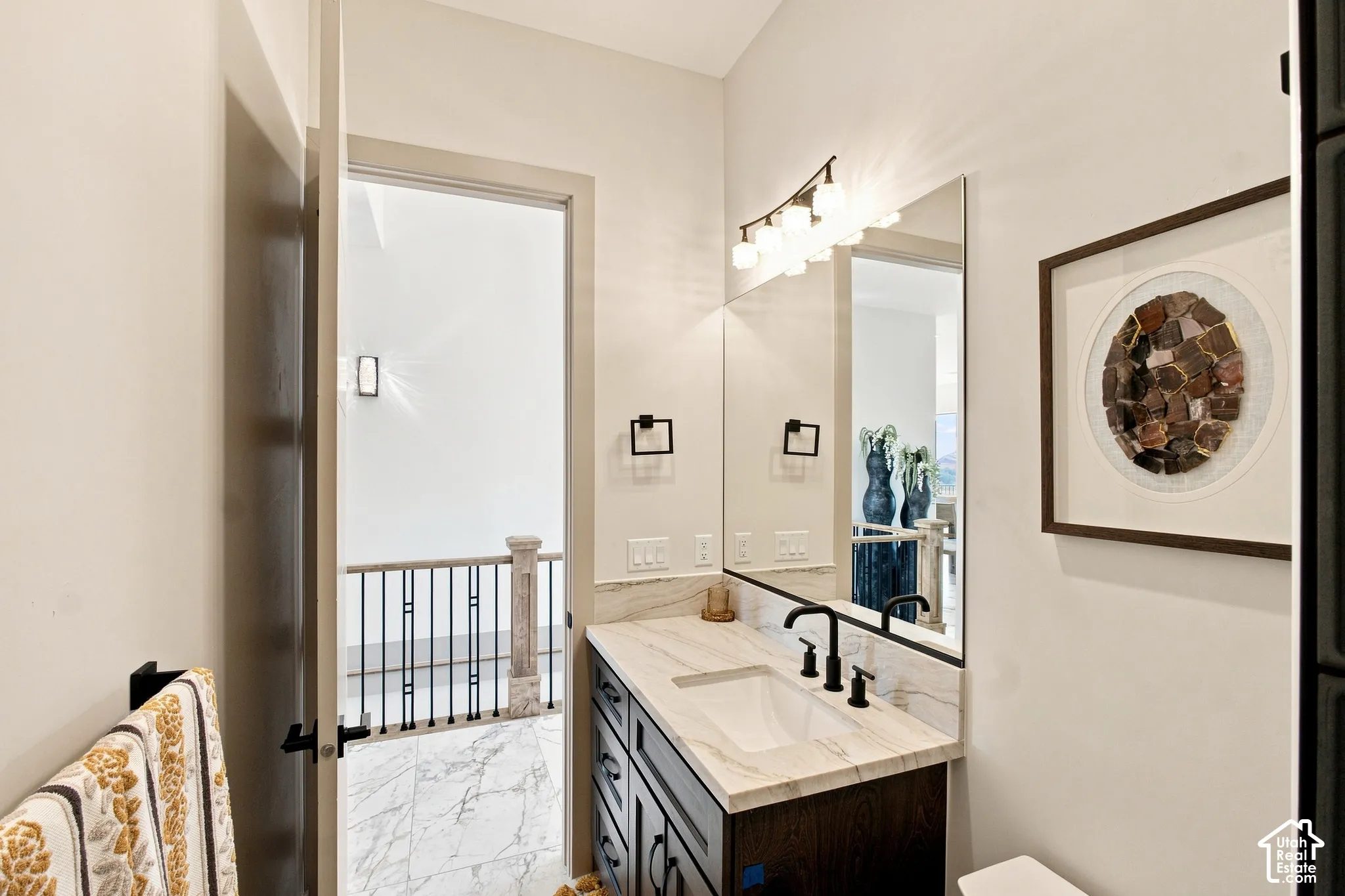 Vanity featuring a rectangular undermount sink, a light-toned countertop, and dark-finish cabinetry