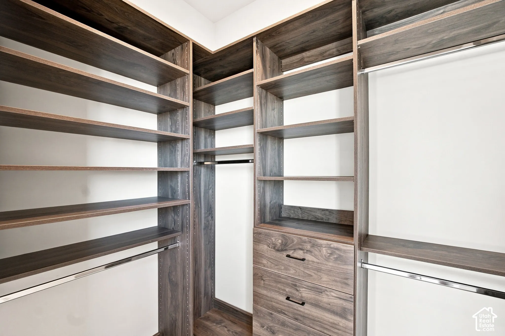 Custom closet system featuring wood-finish shelving, built-in drawers, and chrome hanging rods