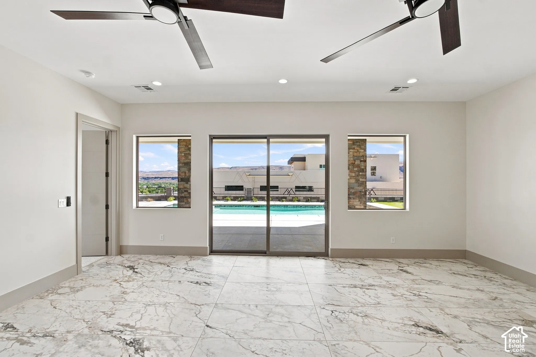Marble-look tile flooring, two ceiling fans, recessed lighting, and a sliding glass door opening to an outdoor pool