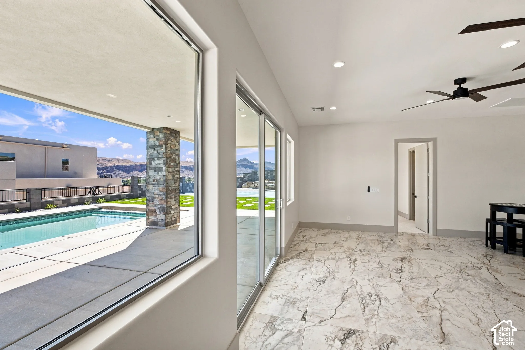 Polished stone flooring, recessed lighting, and a ceiling fan enhance the interior space