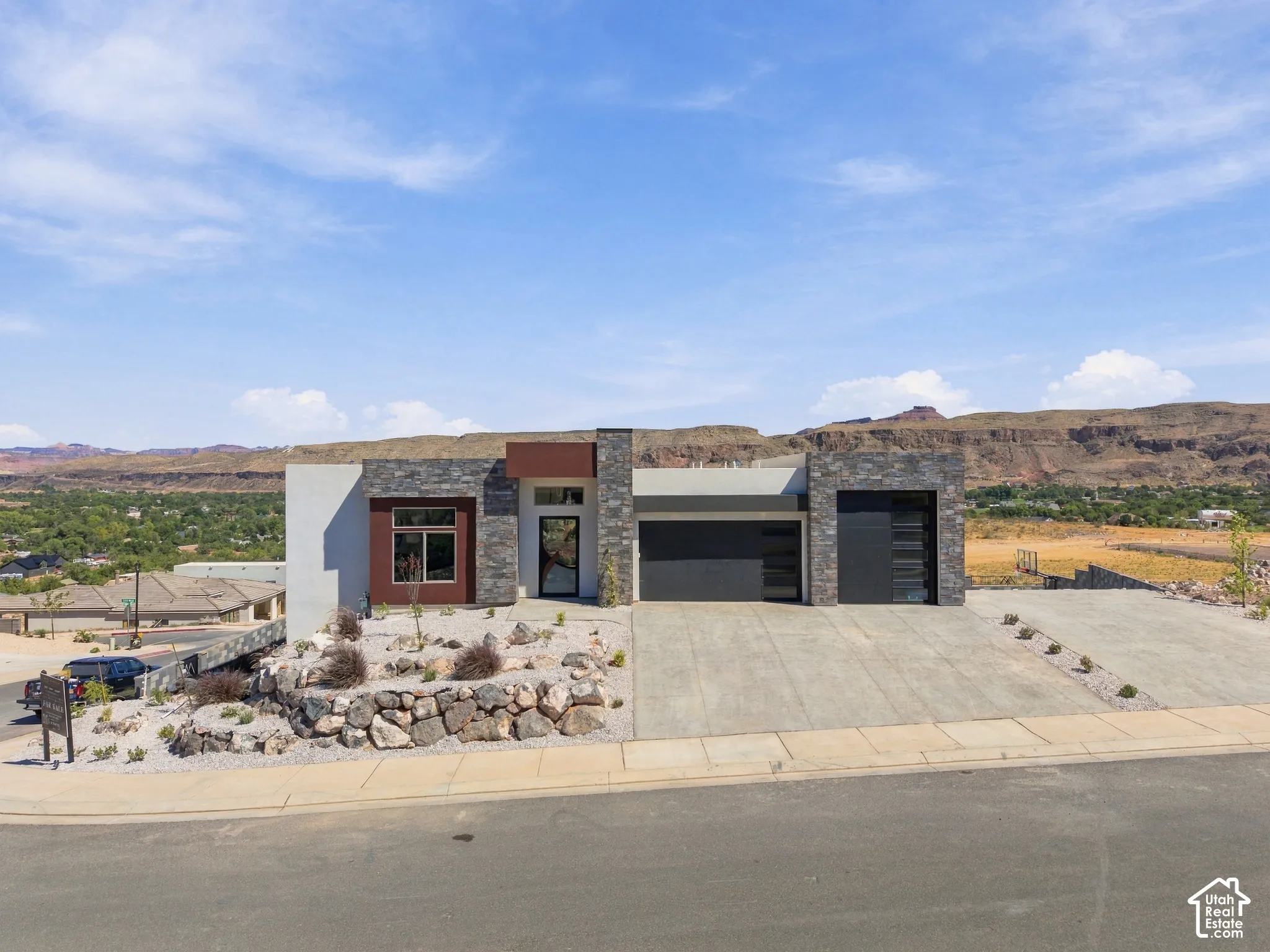 Modern exterior featuring stone and stucco finishes, a multi-panel garage door, and desert-inspired landscaping