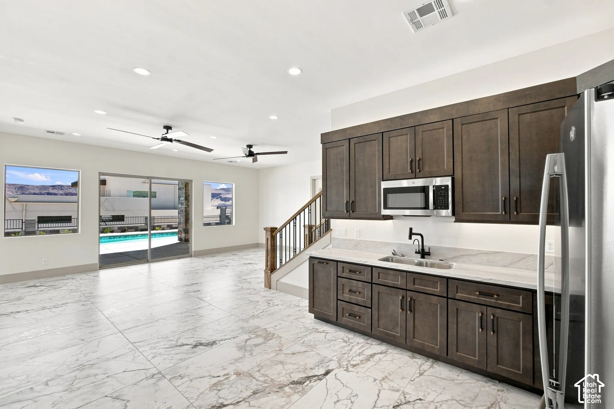 Marble-look tile flooring, built-in wet bar with dark wood cabinetry, stainless steel microwave, and integrated sink