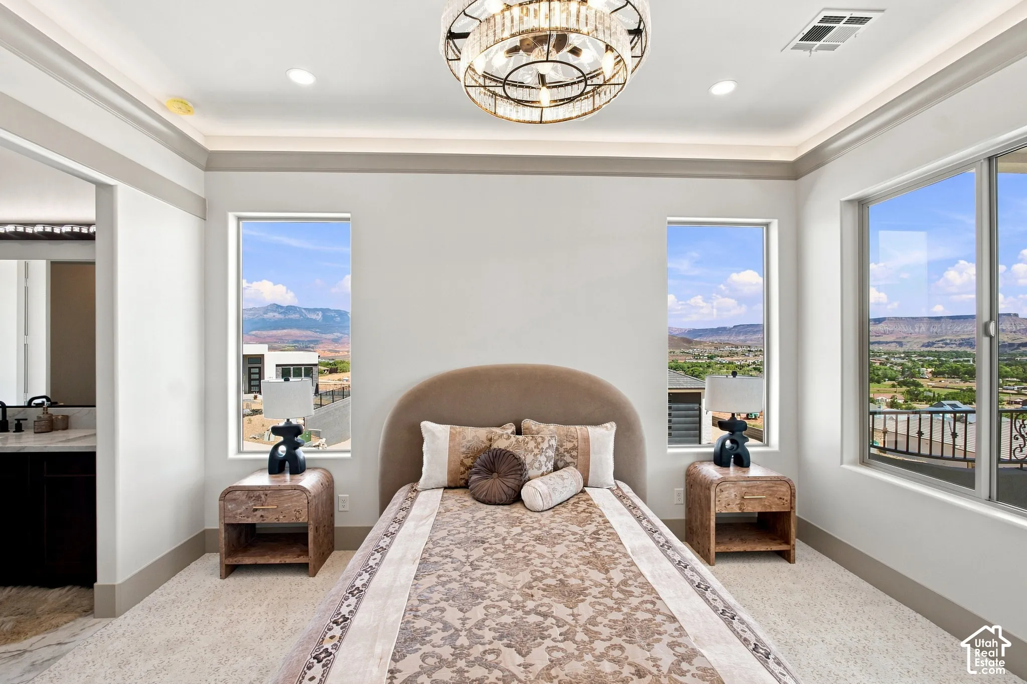 Recessed lighting, crown molding, a decorative chandelier, and an attached ensuite with a vanity and sink