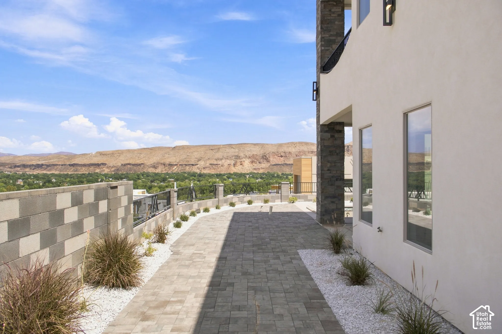Paved patio with decorative stone accents, bordered by a block wall and modern railing