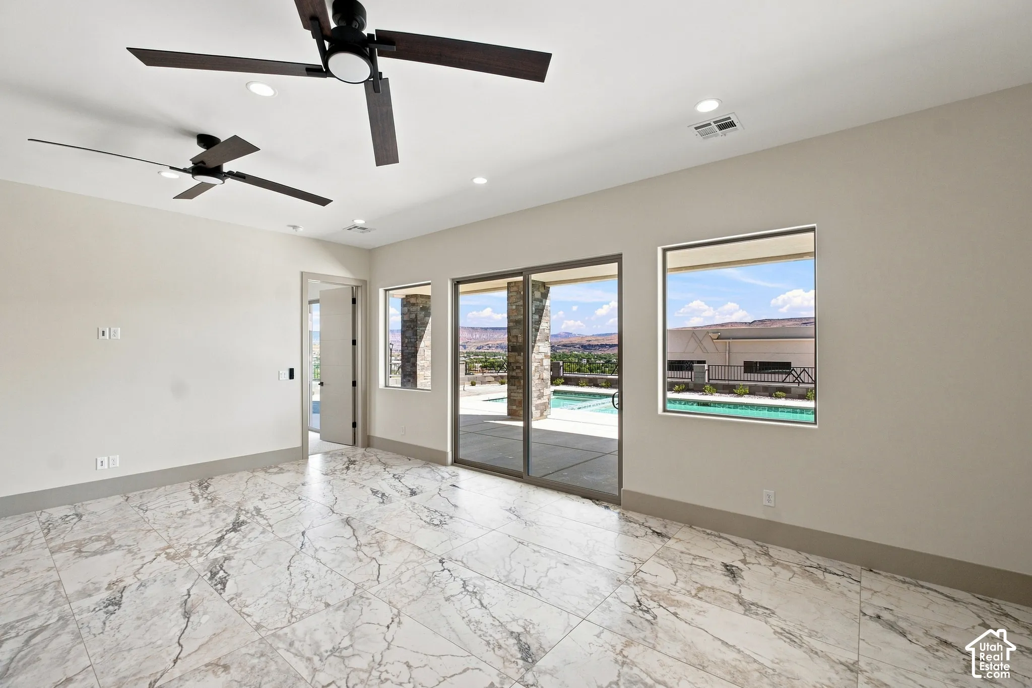 Marble-look tile flooring, two ceiling fans, recessed lighting, and a sliding glass door opening to an outdoor pool area