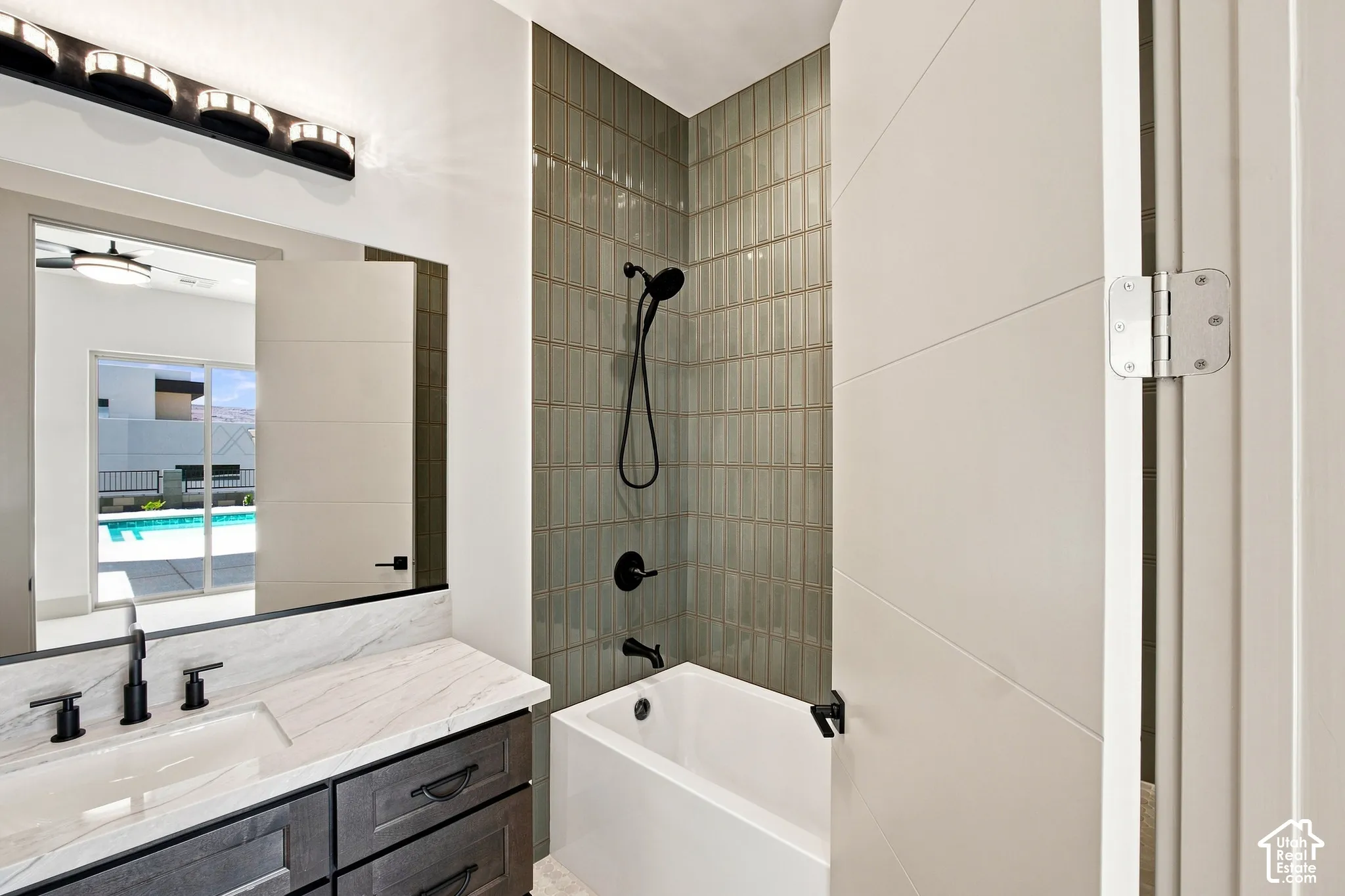 Bathroom with a deep soaking tub, matte black shower fixtures, vanity with a white countertop, and a large wall mirror
