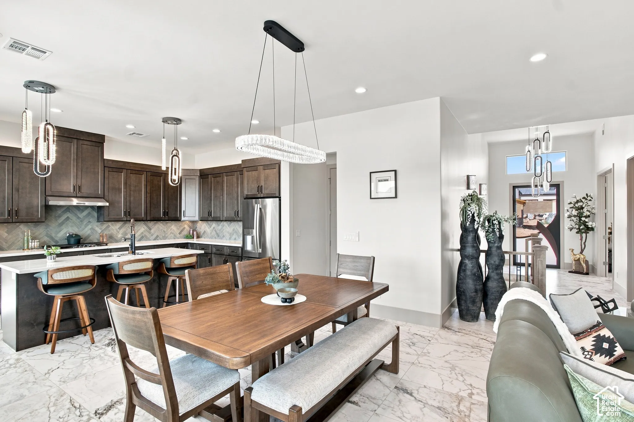 Gourmet kitchen with dark wood-finish cabinetry, stainless steel appliances, and a chevron tile backsplash