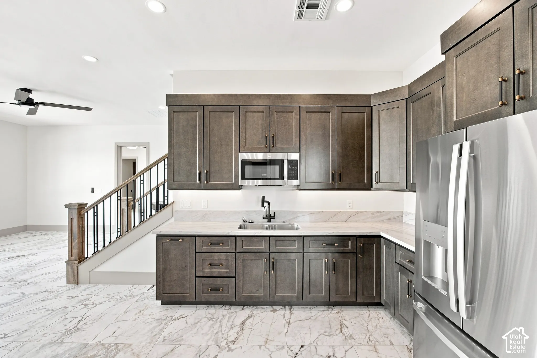 Built-in wet bar with wood-finish cabinetry, stainless steel appliances, and a solid surface countertop