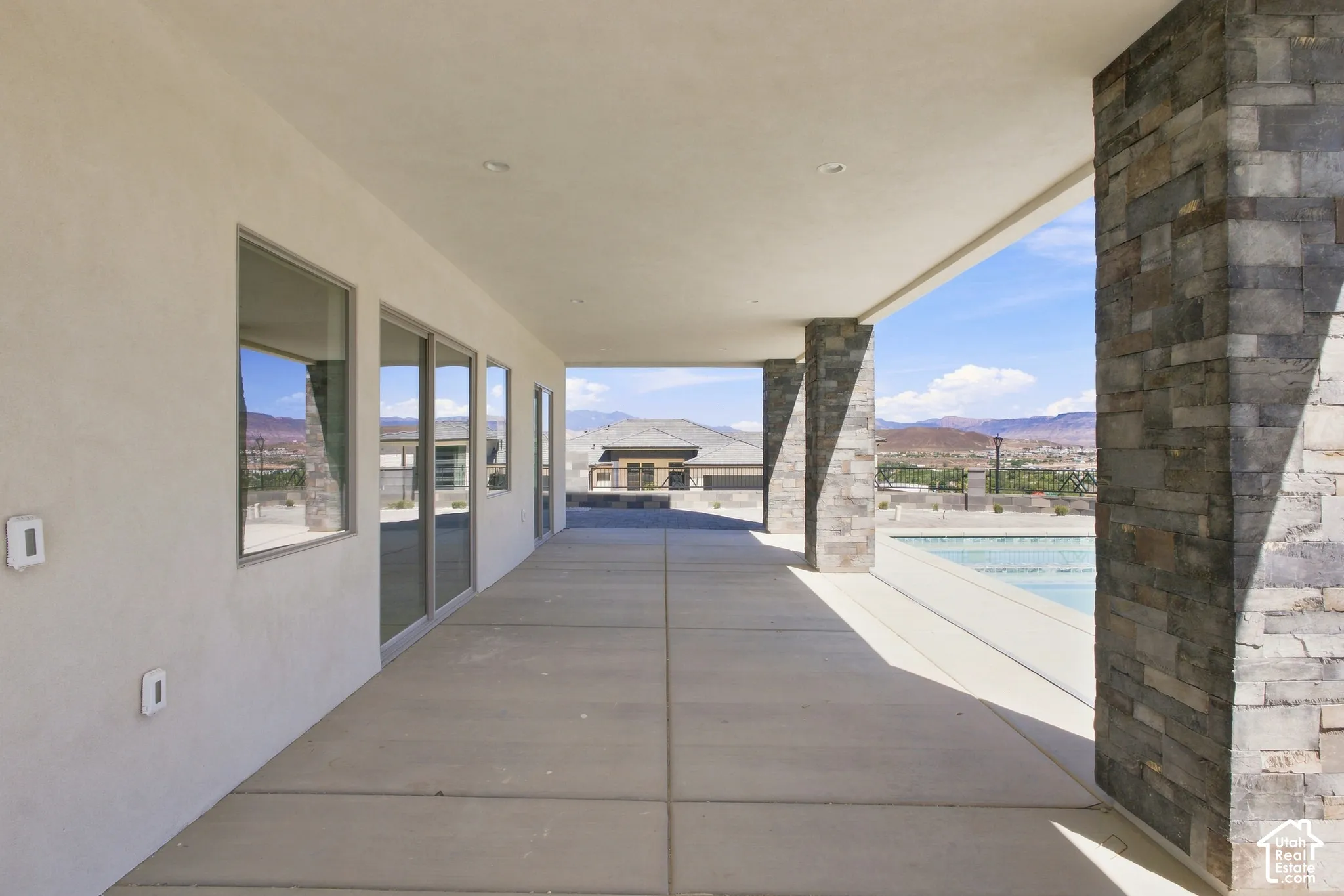 Covered outdoor patio with stone-clad columns, recessed lighting, and a concrete surface