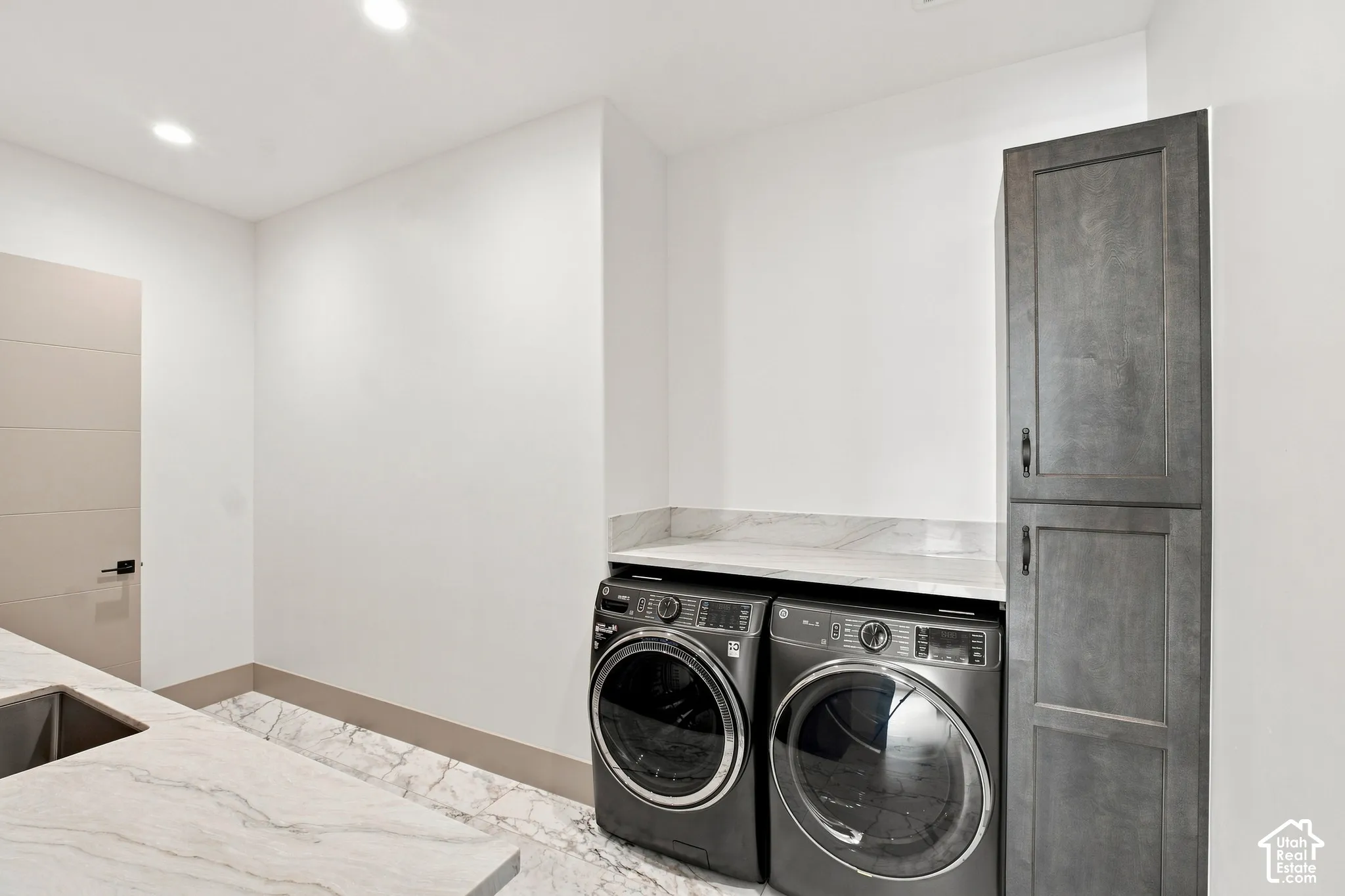 Laundry area with integrated sink, stone countertops, and built-in storage cabinetry