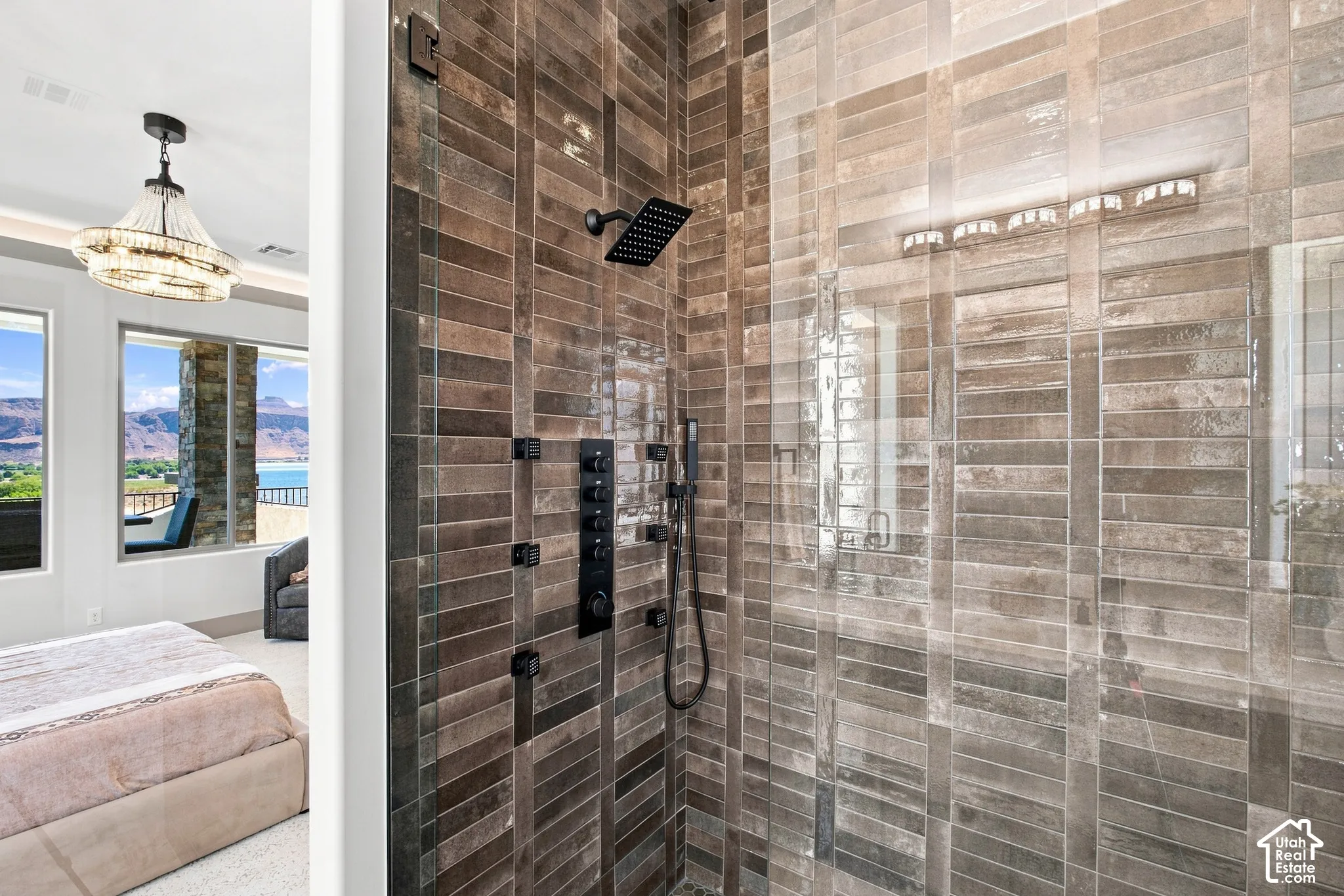 Spacious shower featuring full-height tiled walls, glass enclosure, and matte black fixtures