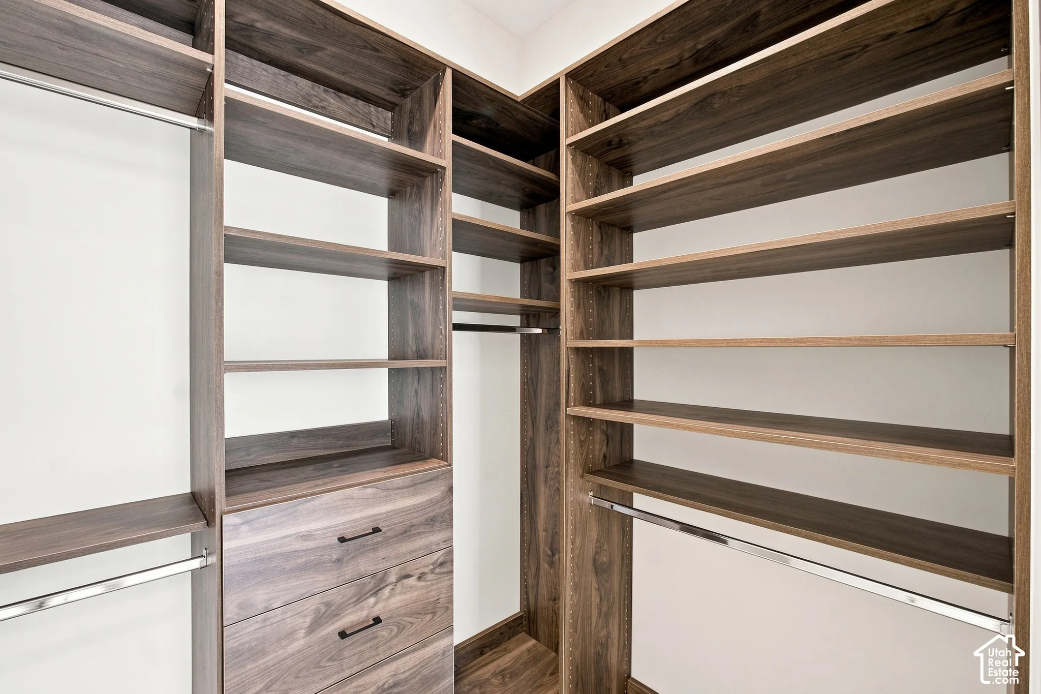 Custom closet system featuring wood-finish shelving, integrated drawers, and chrome hanging rods